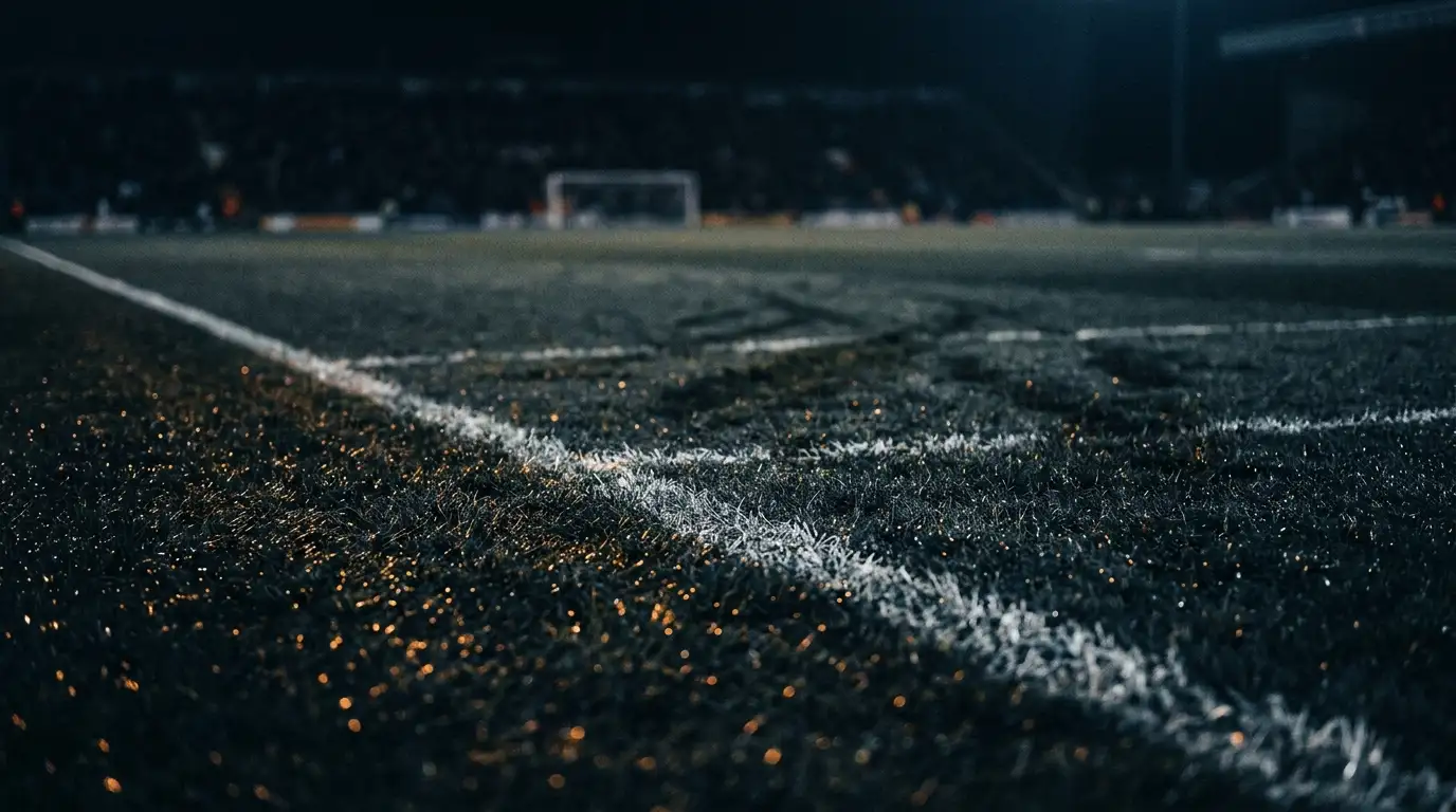 Terrain de football vu au ras de la touche, avec lignes convergentes et éclairage ambré